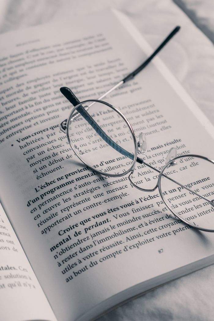 our-services-04 A close-up of eyeglasses on an open book with text in French.
