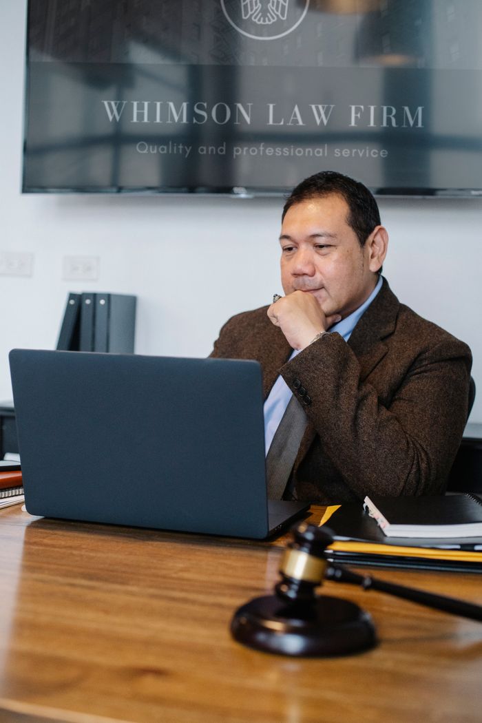 MSB Registration in Canada: A Compliance Checklist for Money Services Businesses Concentrated Asian male lawyer wearing classy formal suit working on netbook while sitting at table with decorative hammer of justice in modern law office