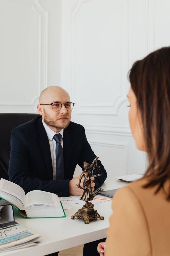 portfolio-img-03 A lawyer consulting with a client in a modern office featuring Lady Justice.