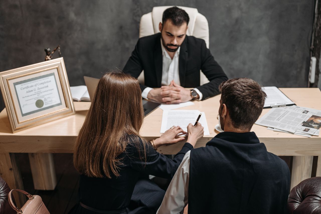our-services-06 A lawyer discusses legal documents with clients in an office setting.