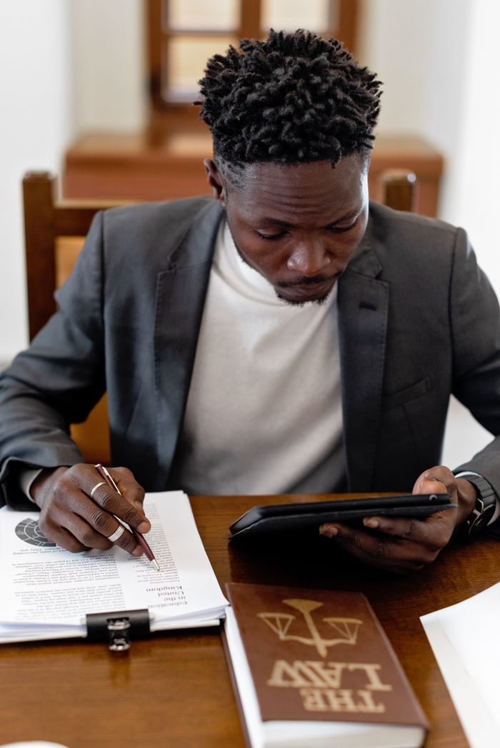 Why Trademark Registration Is Worth It for Early-Stage Businesses Businessman in black suit working with documents and tablet at an office desk.